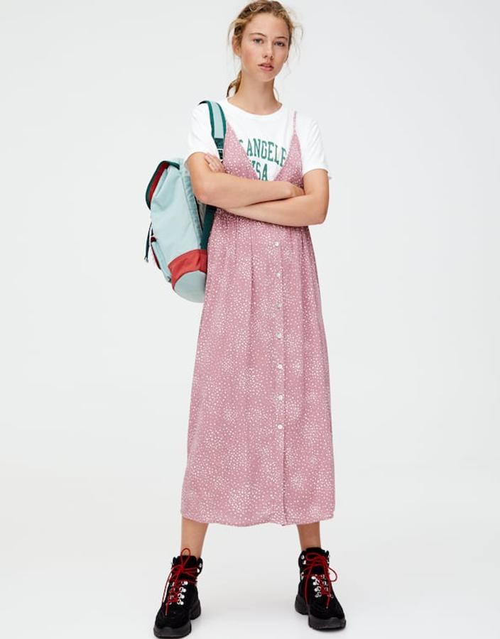 Vestido midi rosa con motitas blancas estampadas de Pull&Bear (22,99 euros). Lleva tirantes finos y cierra en el delantero con botones. Botas de trekking con dible cordón, cuello acolchado y tirador en la parte trasera (Pull&Bear, 39,99 euros).