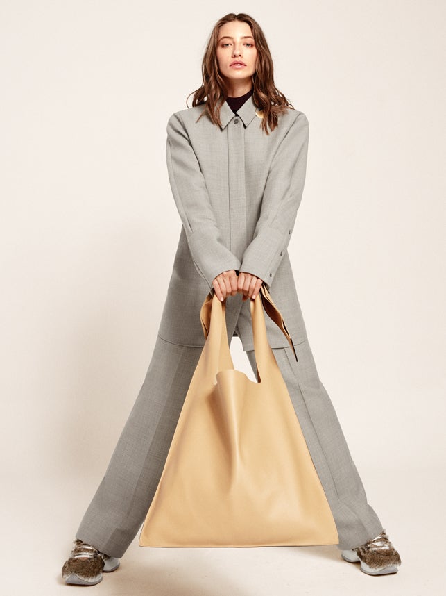 Jersey, camisa y pantalón de Cos. El bolso oversize es de Loewe y las zapatillas, de Hogan.