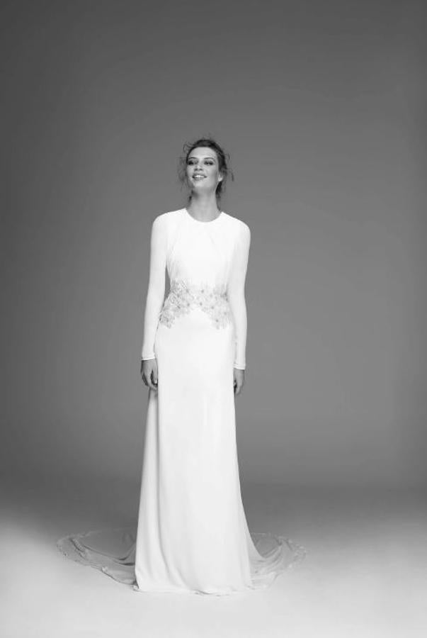 Vestido de crepé y gasa con cuello a la caja y manga larga. Tiene el escote drapeado y la espalda al aire pero lo que más destaca del vestido es la cintura cuajada de flores bordadas hasta la cadera.