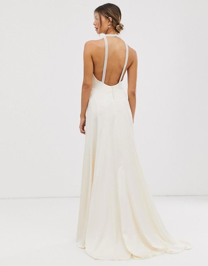 Las líneas minimalistas se adueñan de este vestido de novia en satén marfil con detalles joya y espalda al aire de Asos (165.99 euros), que derrocha sofisticación y feminidad.