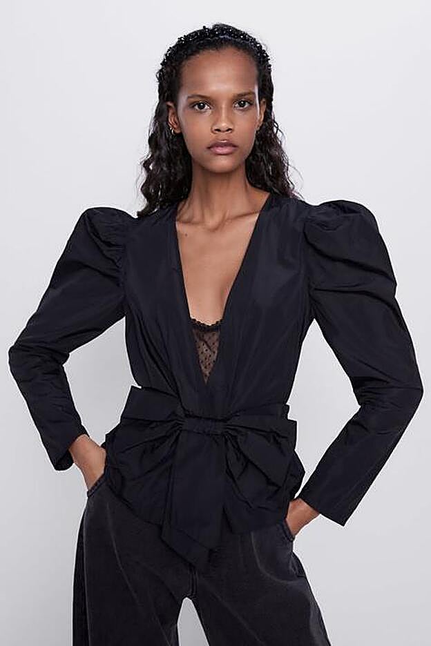 Blusa de tafetán negro con mangas con volumen y lazada delantera, de Zara.