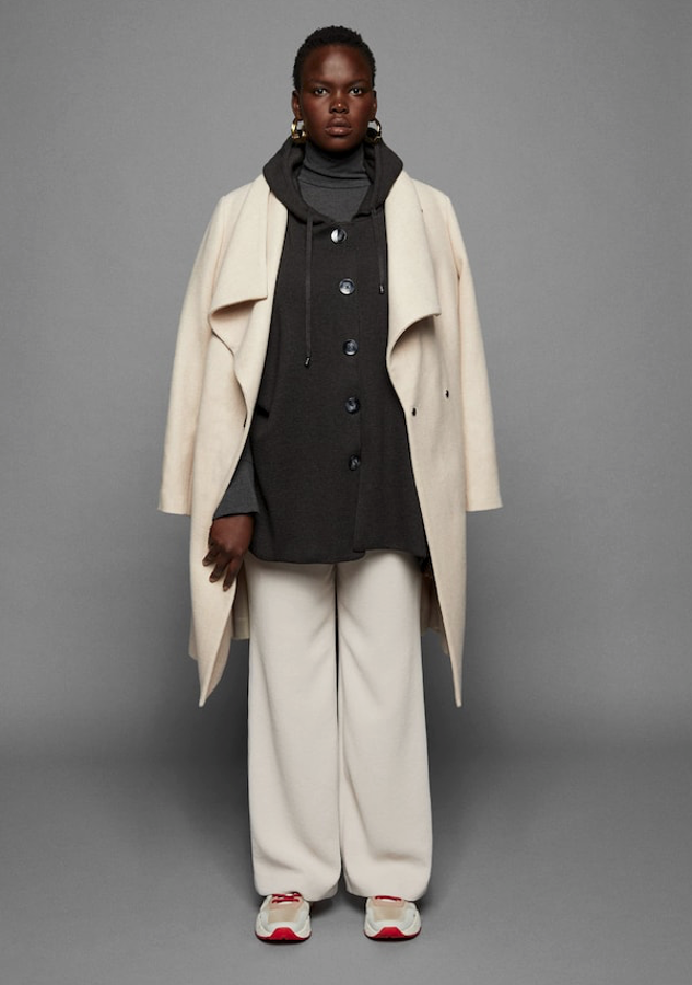 Un look precioso de Violeta: abrigo asimétrico con cinturón desmontable, solapas amplias y forro (129,99 euros). Pantalón palazzo con dos bolsillos laterales y otros dos con ribete en la parte posterior (39,99 euros). Poncho de algodón en tejido de punto con manga corta y capucha desmontable (59,99 euros). Deportivas maxi multicolor (49,99 euros), con una plataforma de 4 centímetros.