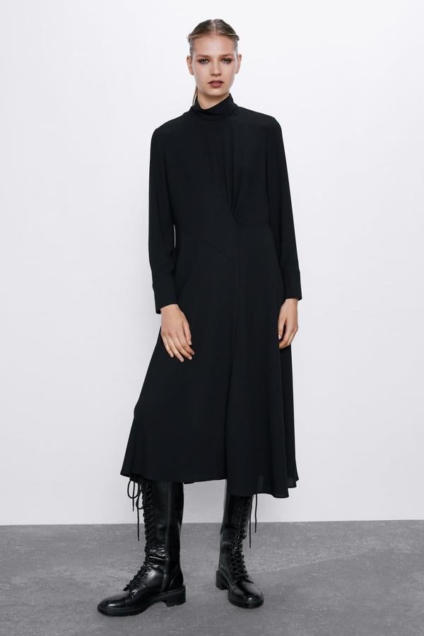 Vestido midi fluido de línea evasé, con el cuello subido y manga larga. Lleva un frunce en el delantero y cierra en la espalda con una cremallera oculta (Zara, 39,95 euros). Bota plana de piel de color negro con cordones, punta cuadrada y tirador trasero (Zara, 99,95 euros). La suela es gruesa tipo track y cierra con una cremallera interior.
