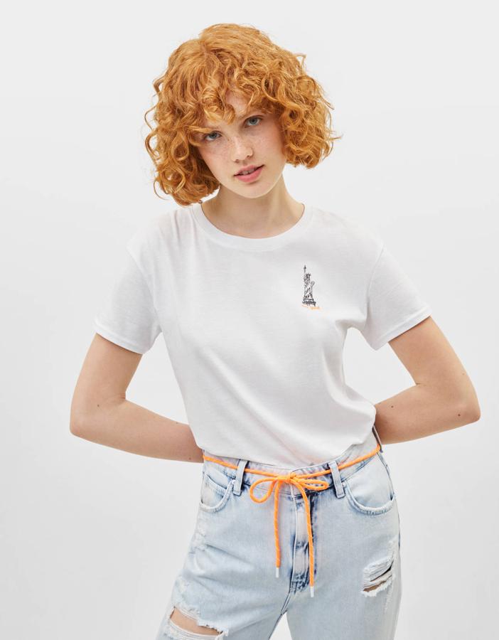 Una de nuestras preferidas, por mininalista y por neoyorkina. Sobre el pecho izquierdo y encima del nombre de la ciudad en contraste, un pequeño dibujo de la estatua de la libertad.