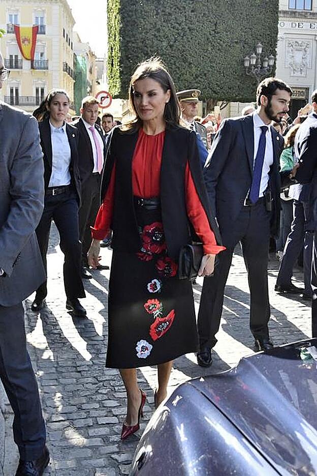 Letizia ha llevado a Sevilla un look en negro y rojos, dos de sus colores favoritos. Una falda de flores, una blusa y una capa negra low cost de Zara.
