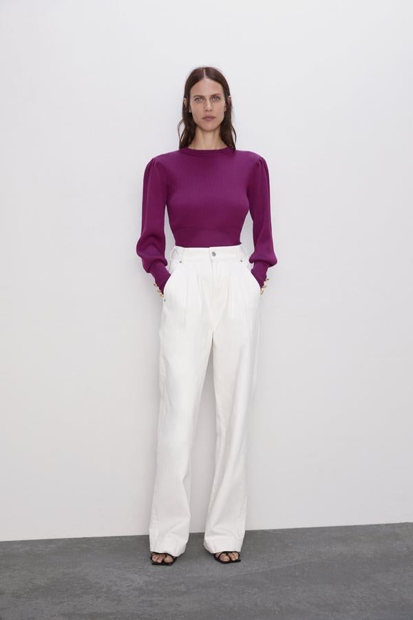 Con puños anchos acabados en botones dorados y mangas abullonadas, este jersey de Zara de cintura entallada confeccionado en canalé cuesta 12,99 euros. En color berenjena solo está disponible en la talla M, en negro hay lista de espera para las tallas S y M.