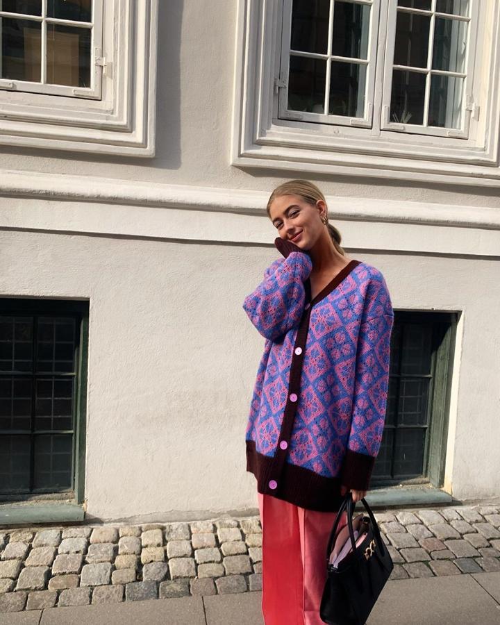 Es raro que lleve el pelo recogido porque, como decíamos, su melena rubia es casi un accesorio más en sus estilismos. Pero en este caso, mejor, así nos deja ver al completo esta maravillosa chaqueta de punto estampada en tonos morados y oversize, que lleva con un pantalón en tono coral.