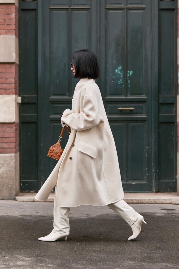 Un abrigo largo blanco con pantalón y botines de tacón bajo.