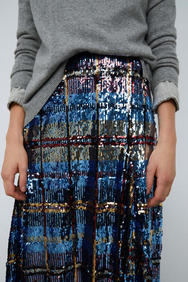 Con vuelo y diseño de cuadros, esta falda midi de Sfera combina los tonos azules con plateados, atravesados por líneas en rojo y color oro. Cuesta 49,99 euros en Sfera.