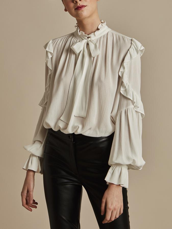 Blusa blanca con volantes de estilo boho (59,99 euros) y pantalón pitillo efecto piel (75,99 euros).