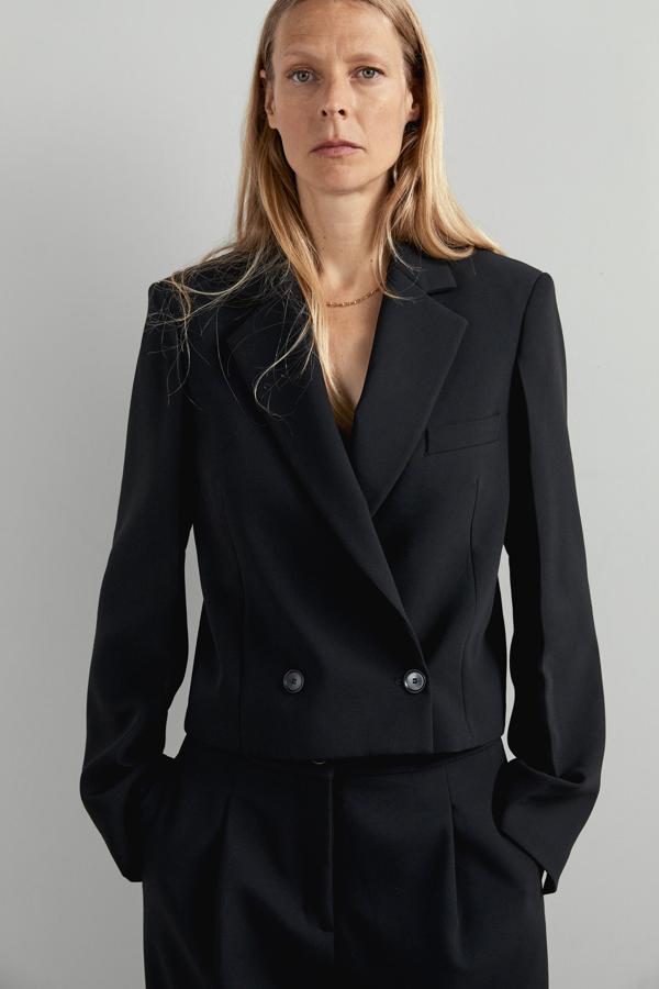 Otra de las versiones en negro de Zara es esta blazer cropped con cierre frontal cruzado y bolsillo en el pecho. Cuesta 49,95 euros y está disponible en las tallas que van de la XS a la L.