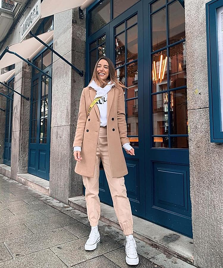 Teresa Bass optó por un look en tonos claros combinando una sudadera blanca con pantalón y un abrigo beige y Converse.