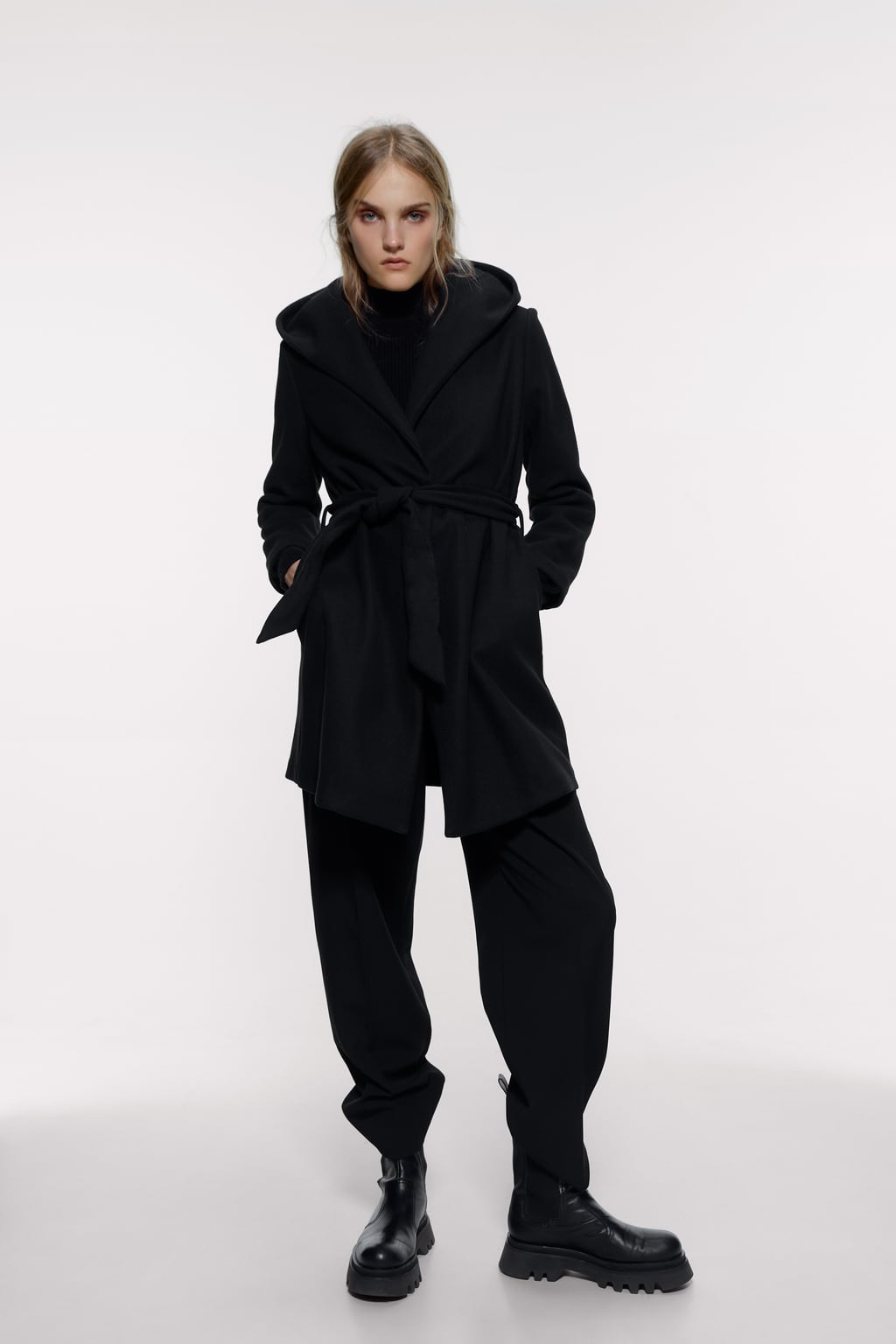 Abrigo negro tipo envolvente con cinturón de Zara. (39,95 euros).