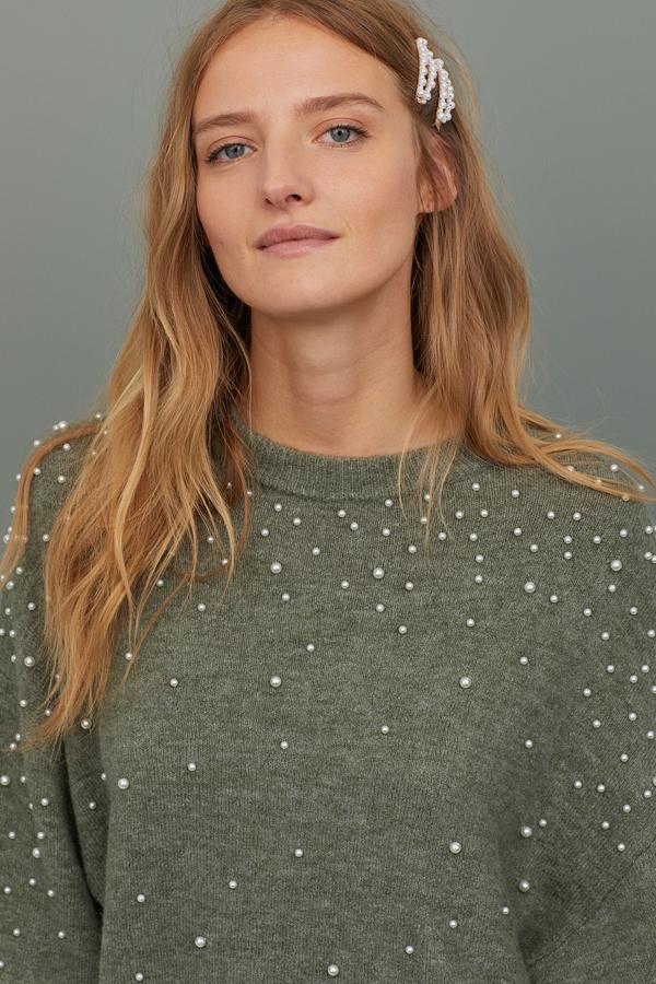Repartidos por toda la prenda, mangas incluidas, el jersey verde caqui con abalorios de H&M recurre a las perlas repartidas en forma de nieve para crear otra interesante versión del jersey con abalorios. Solo quedan, y pocos, en las tallas XS y S.