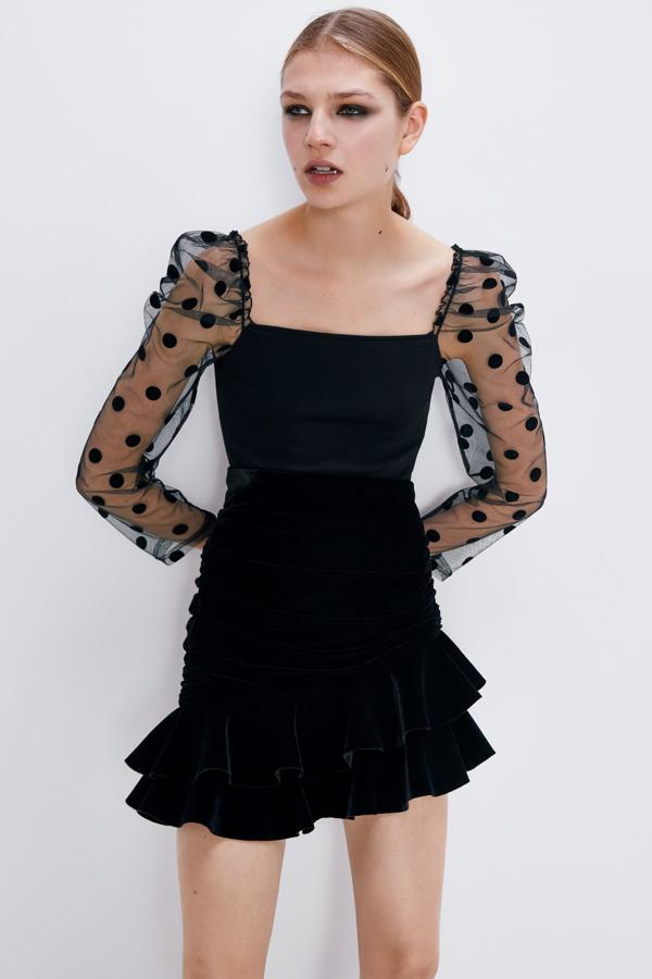 En Zara también apuestan por la manga semitransparente, en esta ocasión en versión larga y con lunares, para este top de escote recto. Cuesta 19,95 euros.