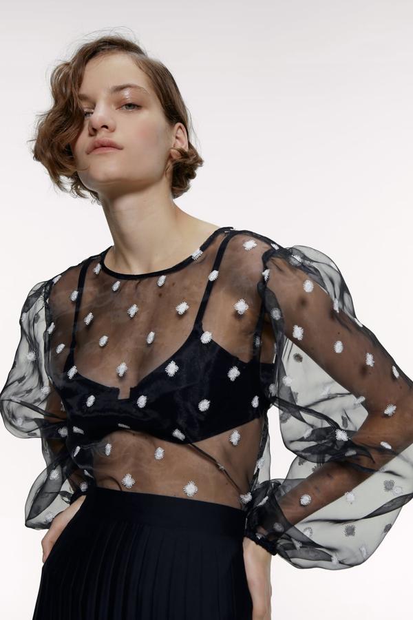 Cuerpo semitransparente con cuello redondo y manga larga acabada en elástico. Va salpicado de bordados combinados a contraste (Zara, 25,95 euros).