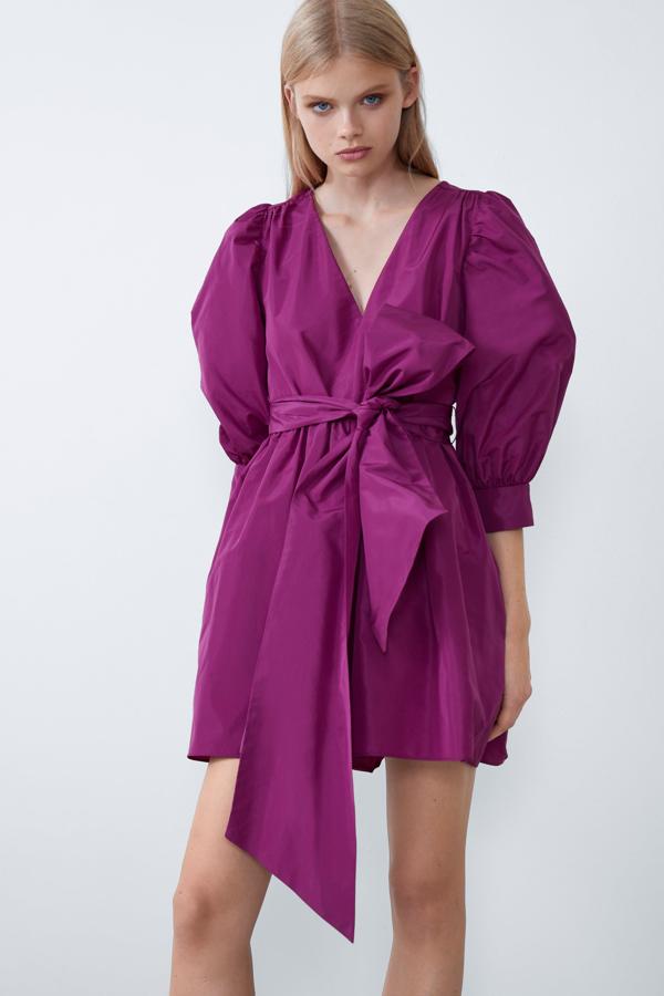 Este mini vestido de tafetán magenta con volumen en las mangas, maxi lazo a modo de cinturón y escote en uve puede servirte como idea para un look de invitada. En las rebajas de invierno de Zara pasa de 29.95 a 19.99 euros.
