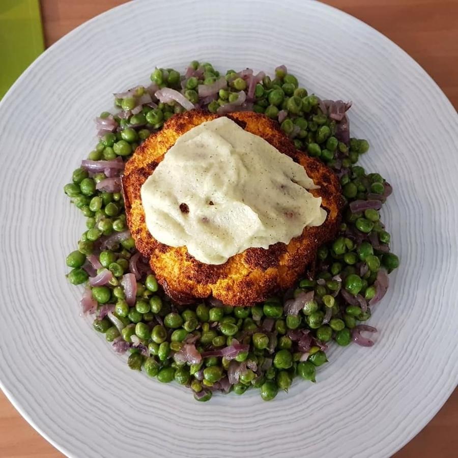 Ingredientes:Coliflor naranjaAOVESalEspecias para la coliflor: cebolla en polvo, pimienta, pimentón, cúrcuma y cominoGuisantes frescosCebolla moradaEspecias para los guisantes: sal, pimienta y ajo en polvoAlioli de manzana Preparación:- Untamos la coliflor con una mezcla de AOVE, sal, cebolla en polvo, pimienta, pimentón, cúrcuma y comino.- La horneamos unos 50 minutos a 180°.- En una sartén, rehogamos los guisantes y la cebolla picada final con sal, pimienta y ajo en polvo.- Emplatamos y servimos con alioli de manzana.Ingredientes para el alioli de manzana:1 manzana1 diente de ajoUnas hojas de hierbabuena1/2 vaso de AOVEUna pizca de sal Preparación:- Pelamos la manzana y el ajo y los troceamos. Los ponemos 2 minutos al microondas para que se ablande.- Ponemos en el vaso de la batidora. Añadimos la hierbabuena y trituramos.- Añadimos el aceite y la sal y batimos empezando desde el fondo del vaso. A medida que vaya creándose una textura cremosa vamos subiendo la batidora.