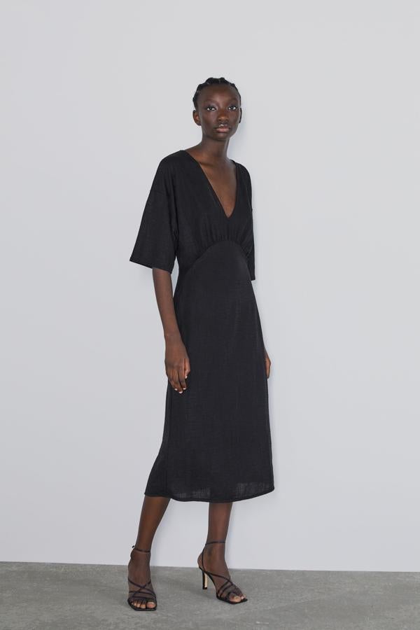 Otro vestido comodín que metemos en nuestra cesta de rebajas de Zara es este diseño midi negro con escote en uve y corte debajo del pecho, que pasa de 19.95 a 12.99 euros.