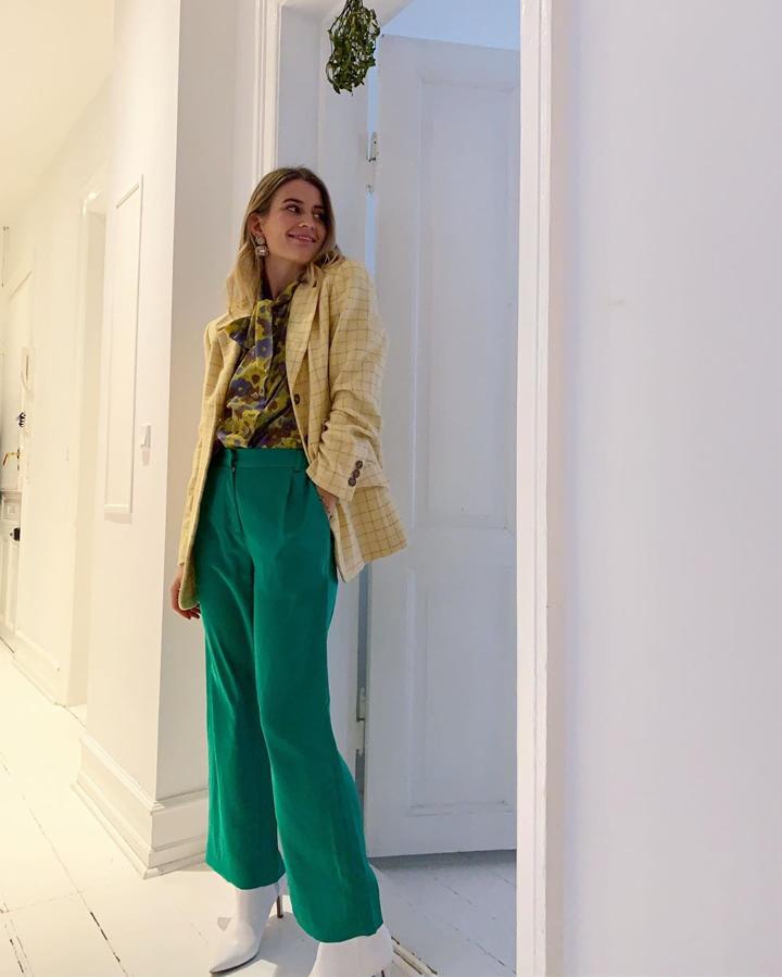 Verde, amarillo y morado. De nuevo esta combianción pero de forma muy diferente: pantalones lisos, blusa con lazada y estampado de flores y una chaqueta de discretos cuadros. Y de nuevo los botines blancos.