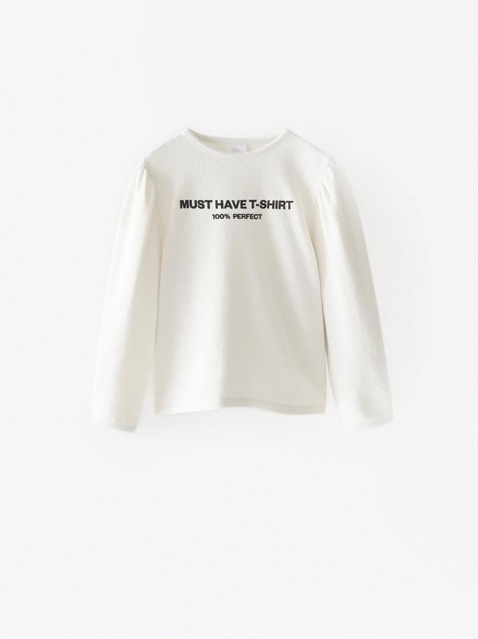 Camiseta manga larga en color crudo y mangas abullonadas con texto. Çostaba 9,95 euros y está rebajada a 6,99 euros.