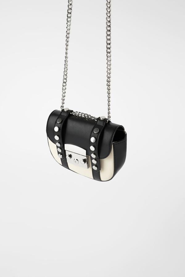 Entre las propuestas de Zara también podemos encontrar esta bandolera en formato mini que combina el negro y el blanco. Con detalles de tachas y pieza metálica en la parte delantera, de 22,95 euros ha pasado a 12,99 euros.