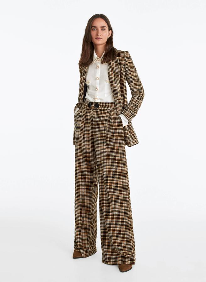 Un traje co personalidad que te quede impecable. Nosotras estamos enamoradas de este de chenilla con estampado de cuadros en tonos tierra de Uterqüe. En las rebajas, la chaqueta pasa de 159 a 99.90 euros; y el pantalón, de 119 a 59.90 euros.