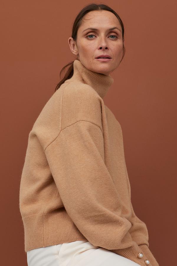 Con cuello vuelto y ligeramente oversize, lo mejor de este jersey camel de las últimas rebajas de H&M son los detalles de perlas en las mangas (19,99 euros).
