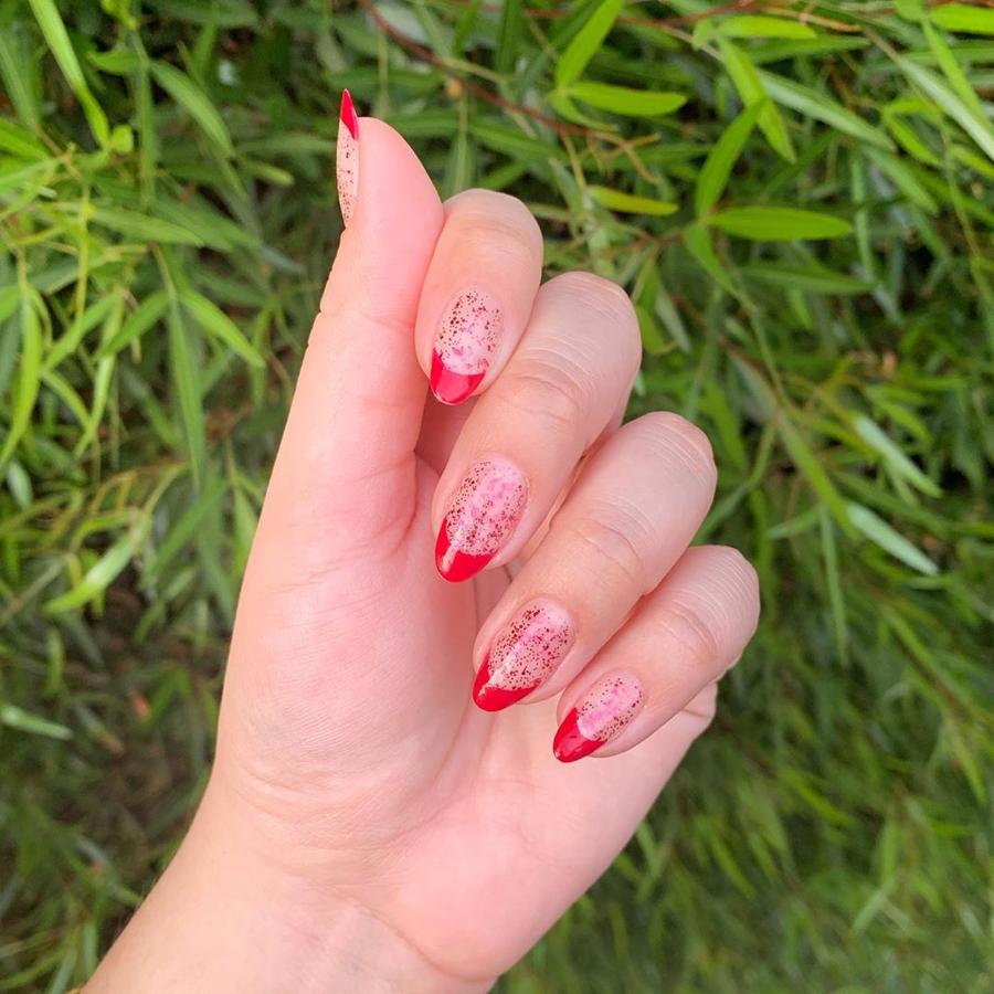 Para este look de uñas se combina una fina capade brillo con la punta en color rojo. Es uno de nuestros favoritos.