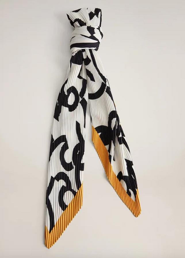 Diseño plisado y tres tonos para esta pañuelo de Mango que cuesta 15,99 euros. Blanco con dibujos negros y encuadre en amarillo, puede ser el alivio tonal de cualquier jersey o chaqueta oscuras.