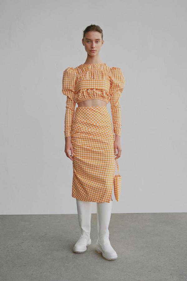 Ya te avisamos, conjuntos como este de Zara de top (22,95 euros) y falda tubo (25,95 euros) en cuadros vichy naranja, levantan el ánimo. Y buena falta nos hace.