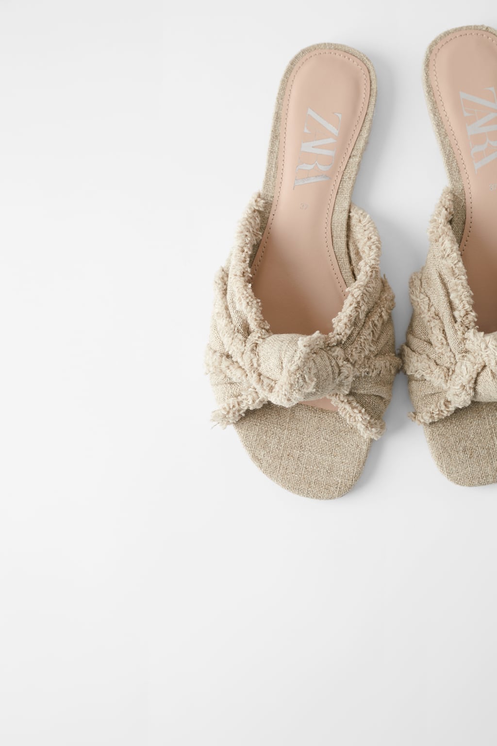 Sandalia plana con nudo desflecado en color beige de Zara. Antes: 29,95 euros. Ahora: 15,99 euros.