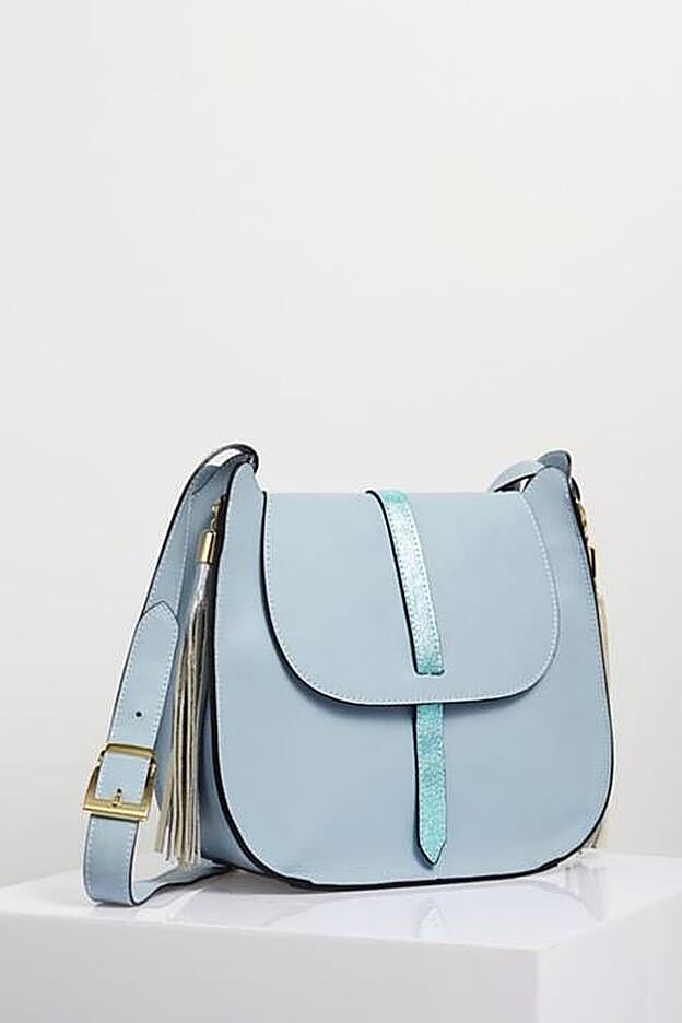 Un bolso en piel azul cielo con solapa y adorno de borlas, disponible en Zalando.