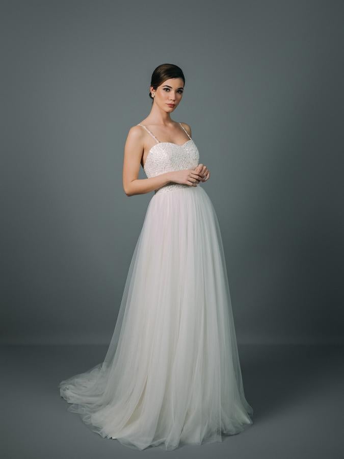 Vestido de novia con escote corazón y cuerpo entallado confeccionado en guipur y lentejuelas. Corte en la cintura y voluminosa falda de tul con cola.