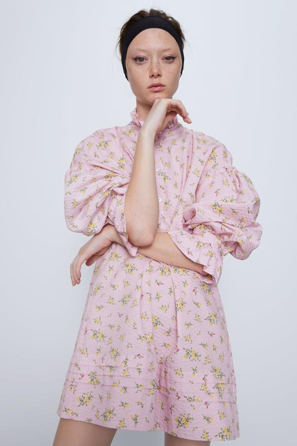 Vestido corto de cuello subido y manga larga acabada en volante. Bajo acabado con pliegues. Cierre frontal con botones.