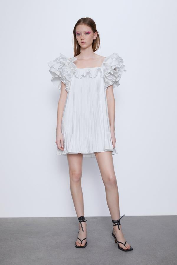 Vestido corto de escote recto amplio y manga a la sisa. Detalle de volantes con volumen. Forro interior.