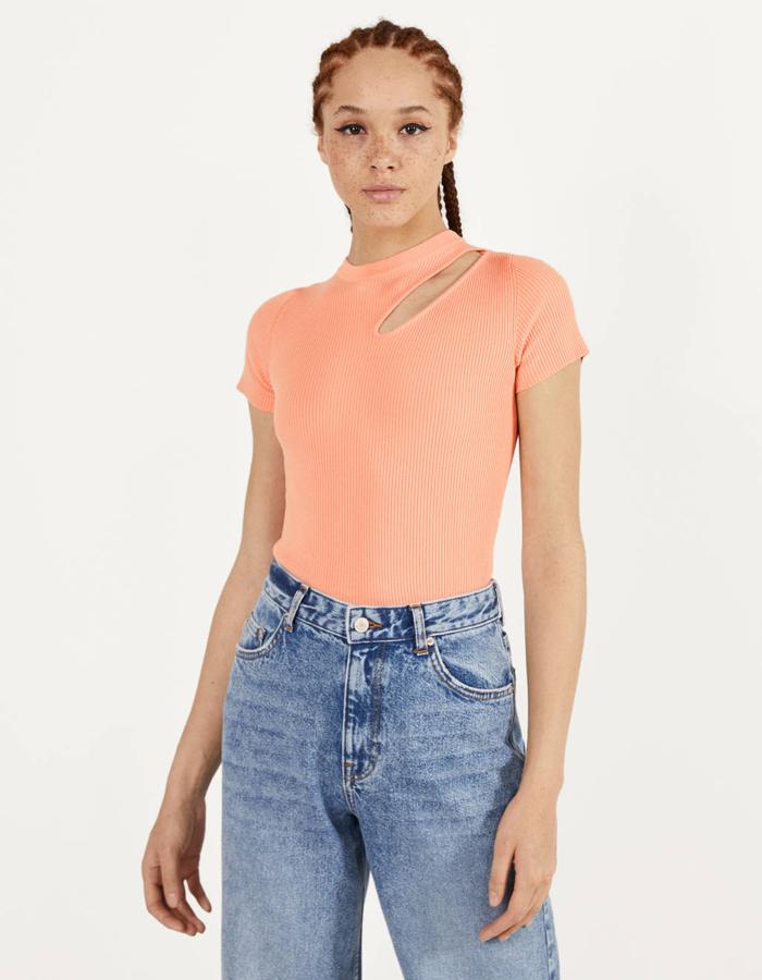 En Bershka hemos encontrado esta camiseta con abertura en el hombro en un ideal color melocotón que nos ha conquistado. Cuesta 12,99 euros, está disponible entre las tallas Xs y L y también se ha lanzado en color negro.