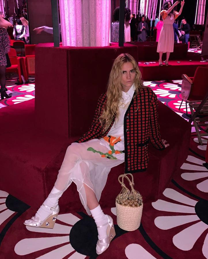 Puede que esta mezcla sea la que más choca, pero no es la mejor de este look. Nos encanta cómo ha elegido un vestido de organza 100% romántico y lo ha combinado con una prenda de punto que es máxima tendencia: cárdigan de cuadros. Un outfit de Miu Miu que ha llevado, precisamente, al desfile de la firma en París.