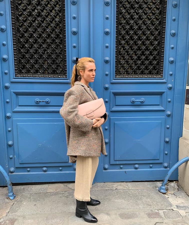 Se nos hace raro verla tan sobria. Un traje con americana oversize en tonos beige y gris, unos botines negros (que podríamos tener cualquiera en el armario) y un bolso rosa que rompe un poco con la monotonía -es de la firma italiana Object Particulare-. Pero lo que nos ha sorprendido es verla con el pelo recogido y un lazo adornando su coleta.