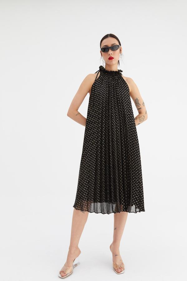 Si quedaba algún lugar al que no hubiese llegado el plisado, Sfera lanza este vestido con escote halter y cuello volante en negro con estampado de cuadros dorados. Cuesta 39,99 euros y está disponible en las tallas S, M y L.