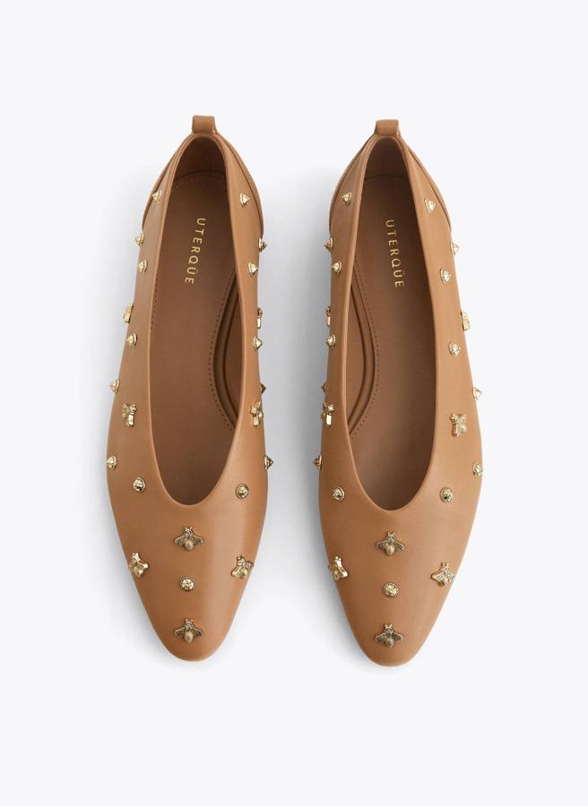 En Uterqüe han querido adornar un modelo clásico en piel marrón con aplicaciones doradas de tachas y abejas (89 euros).