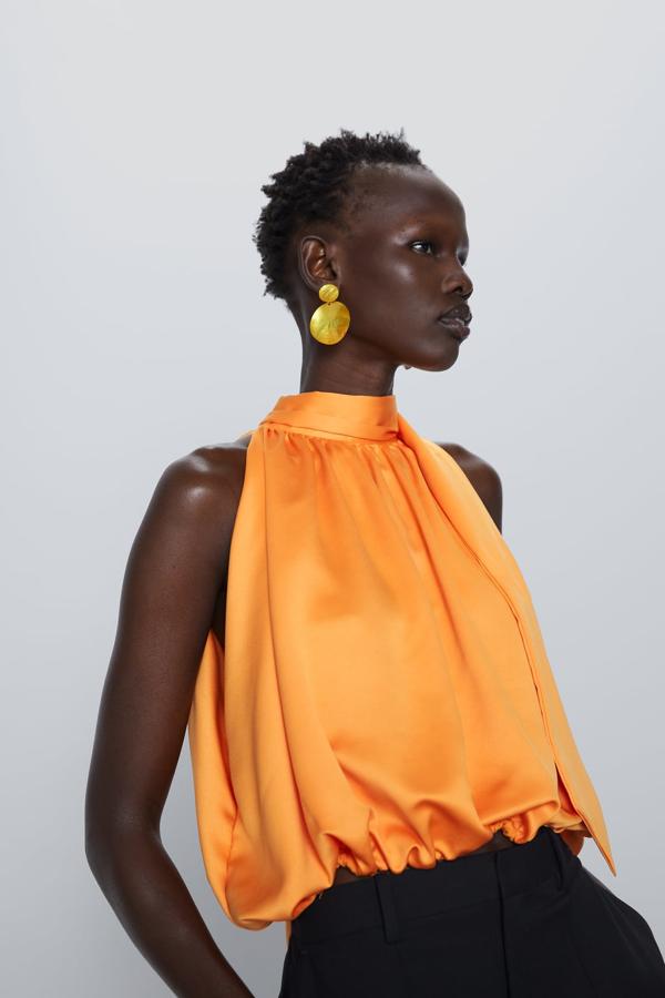 En color naranja, con cuello subido y manga sisa, este top tiene una bonita abertura en la espalda, que termina en lazada a tono. Con bajo acabado en elástico, tiene un precio de 19,95 euros y está disponible entre las tallas S y L.