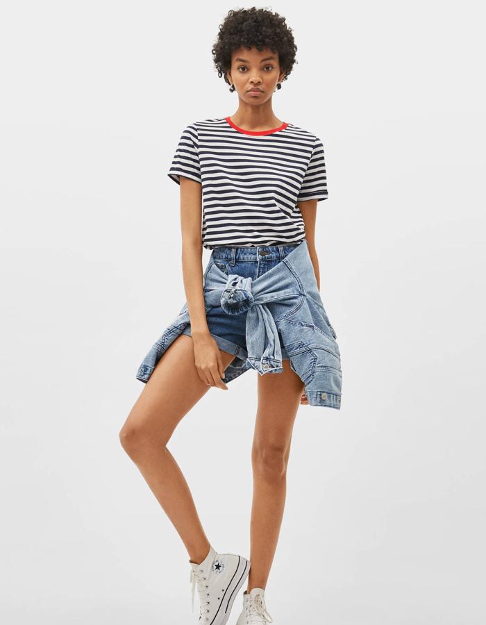 Camiseta de manga corta en blanca con rayas en azul marino. Es de Bershka y tiene el detalle del cuello en color rojo. Disponible de la talla SX a la L, tiene un precio de 5,99 euros.