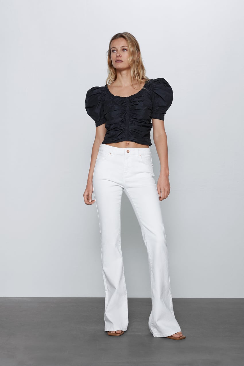 Jeans flare acampanados en tono blanco, de tiro alto, con cinco bolsillos y aperturas traseras en el bajo. Ideales para clavar la estética más setentera. De Zara. (25,95 euros).