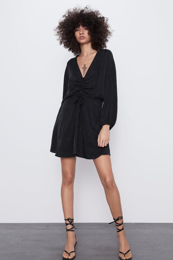 Vestido corto satinado con escote de pico y drapeado ajustable con lazada en el pecho. En color negro, tiene un precio de 15,99 euros y está disponible de la talla XS a la XL.