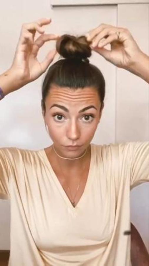 Olvídate del moño a medio hacer y despeinado que seguro llevas a diario en esta cuarentena y opta por uno alto de bailarina como el de Aretha. La influencer lo consigue enrollando la melena que sujeta con una goma del pelo.