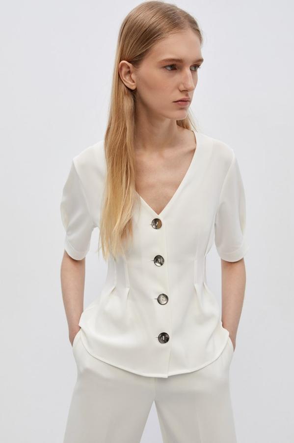 Entre las propuestas más elegantes está esta blusa de manga corta con frunces de Sfera, que tiene cuatro preciosos botones en el frontal en tonos plateados. Cuesta 17,99 euros y está disponible en las tallas S, M y L.