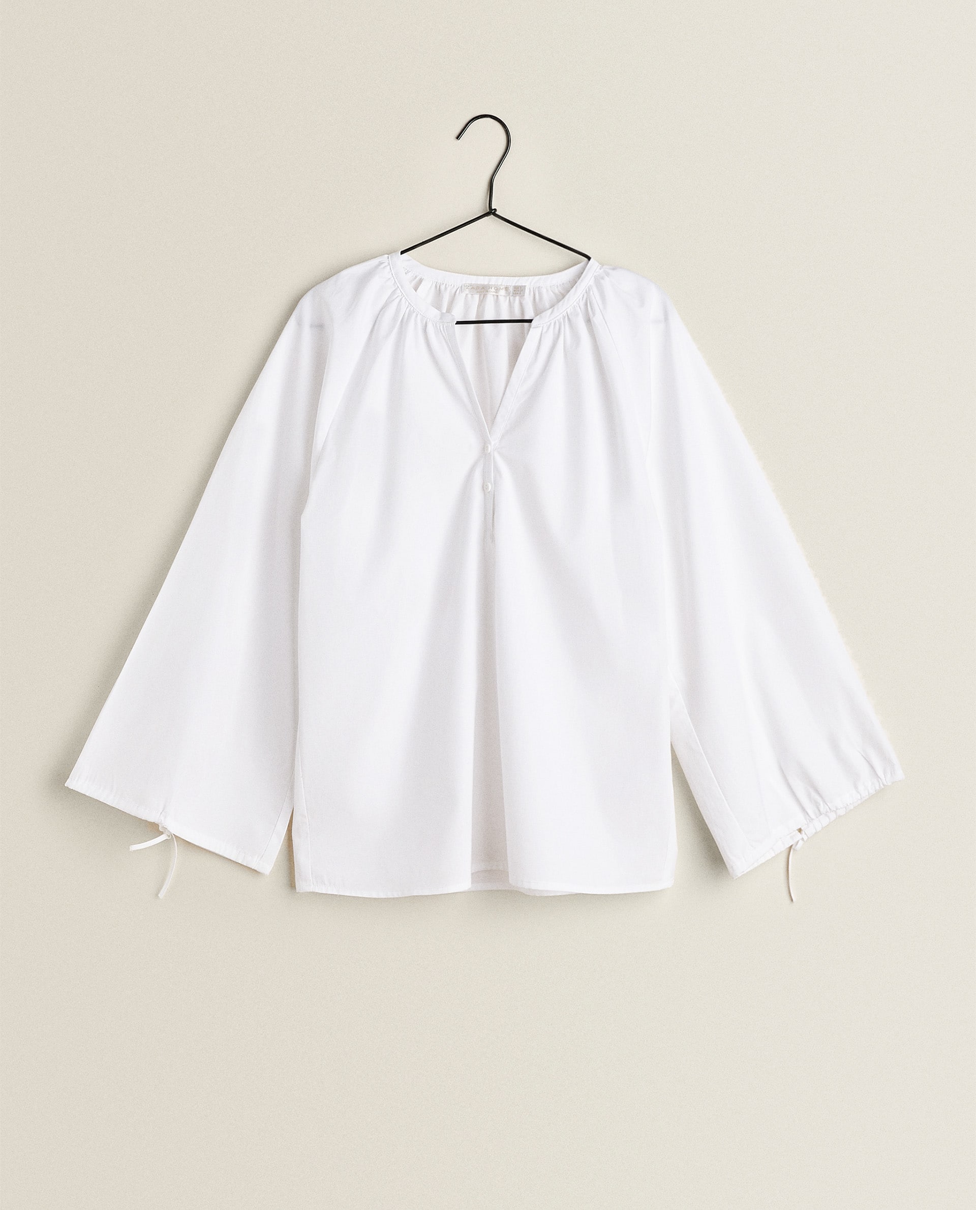 Camisa blanca de algodón de Zara Home con mangas anchas y detalles de lazos. (39,99 euros).