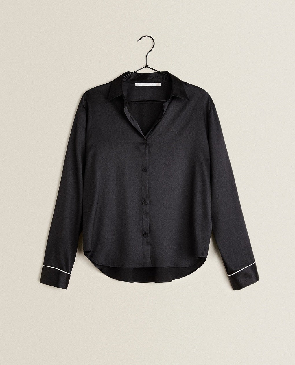Camisa de seda en tono negro liso y contrastes en las mangas. De Zara Home. (69,99 euros).