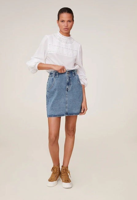 Y al blanco unimos otro clásico, una falda mini vaquera para ponerse las 24 horas del día. Además, este diseño tipo paperbag es un básico perfecto para cualquier silueta. (25,99 euros).